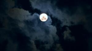 Foto da lua cheia brilhando entre as nuvens